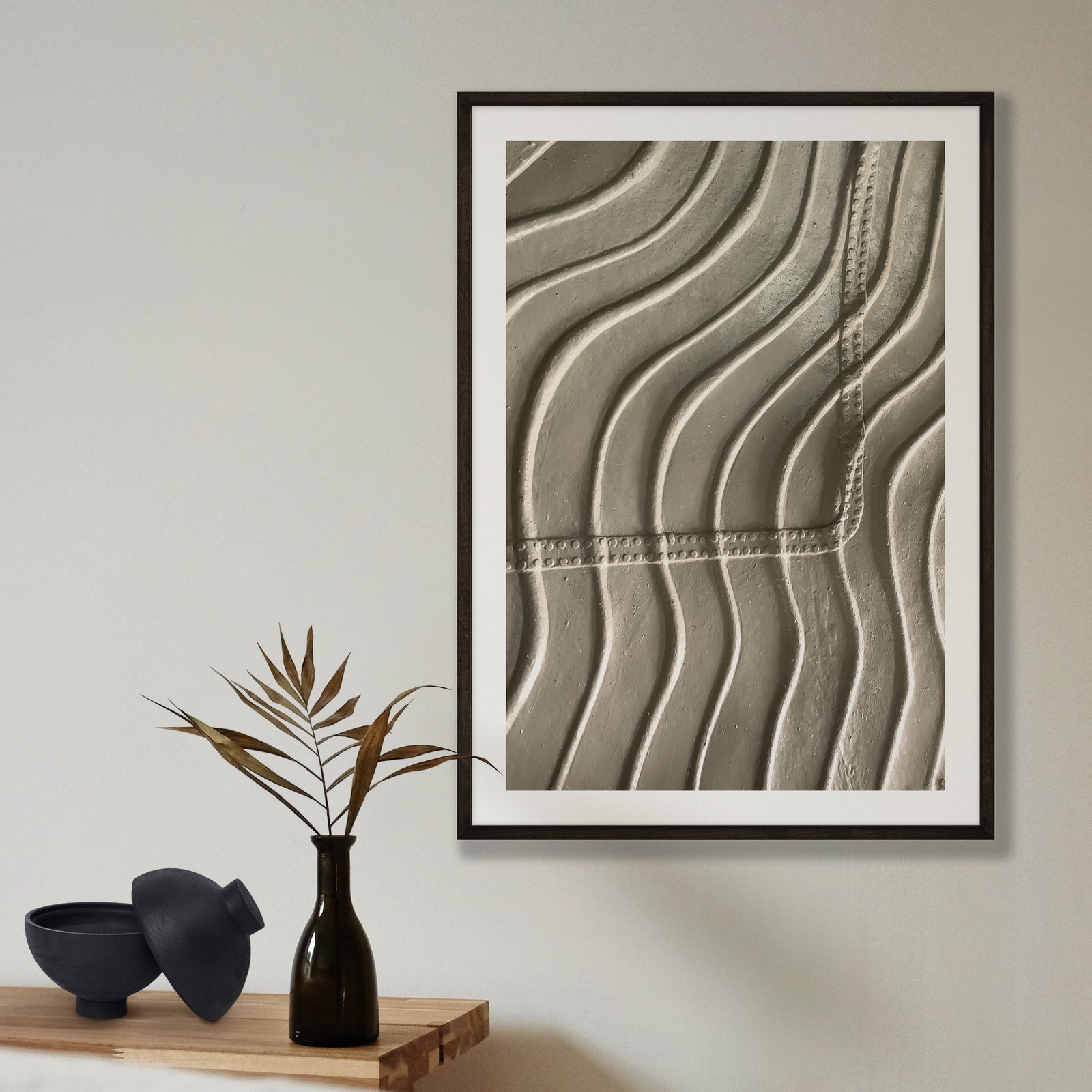 Vertical architectural photograph of the Statue of Liberty's interior ribbed framework and structural curves in a black frame with white mat, hung on a pale beige wall, styled with a minimalist shelf arrangement below featuring a black vase with dried grasses and black ceramic bowl.